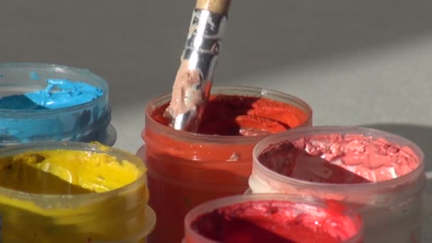 Brush immersed in a jar of orange Acrylic gouache paint. Homewor — Stock Video