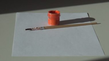 Kağıt, fırça ve bir kavanoz turuncu akrilik guaj boya ta