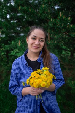 Genç kız yazın tarlada karahindiba topluyor.