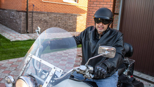 a man on a motorcycle biker in a helmet and a black jacket