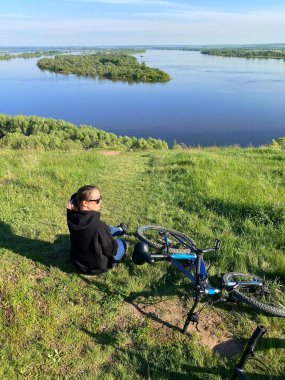 Genç kız gölün kıyısında oturuyor, yaz ve spor