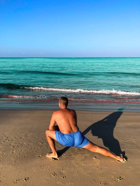 Egzersiz yapan, plajda spor yapan bir adam.