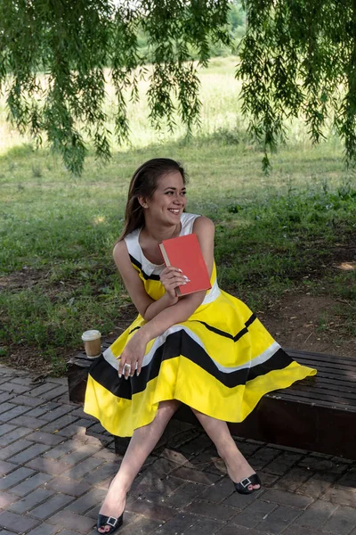 young girl with a coffee and a book in the summer park