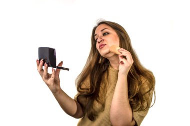 Genç ve güzel bir kadın makyaj malzemesi kullanıyor.