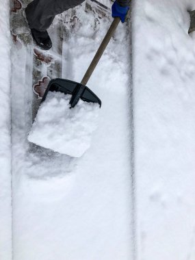 Adam kışın evin yakınındaki bahçesinde kar temizler.