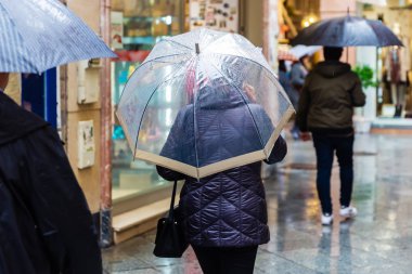 insan yağmurlu bir günde bir alışveriş caddesi şemsiyelerle resim