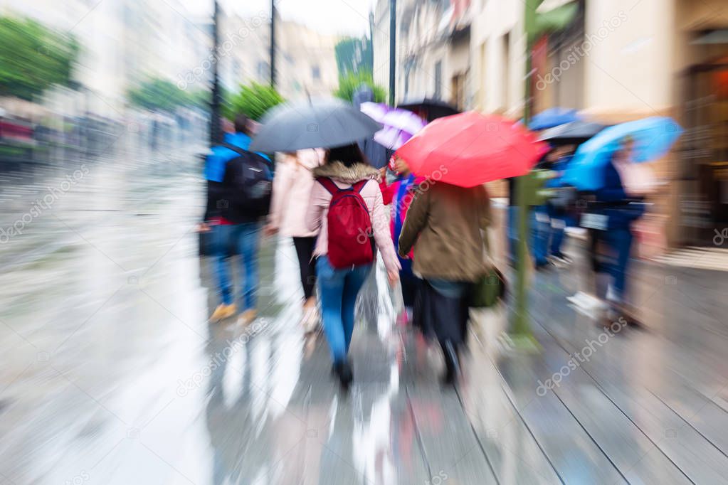 picture of a crowd of people walking in the rainy city with camera made zoom effect