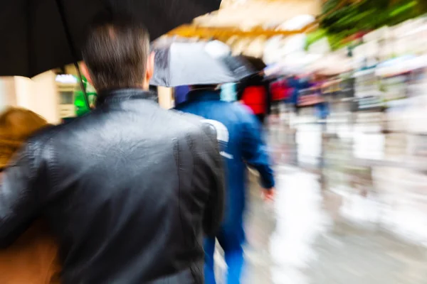 ズーム効果を作ったカメラと雨の多い街で傘を持つ人々 — ストック写真