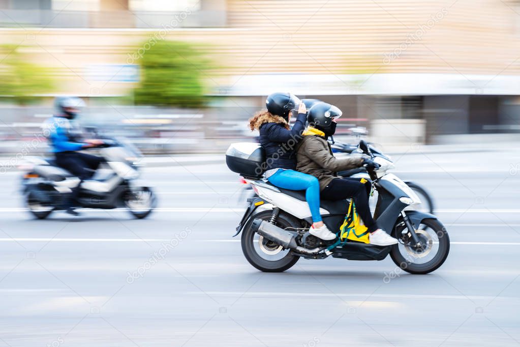 motorcycle rider with pillion in city traffic with camera made motion blur effect