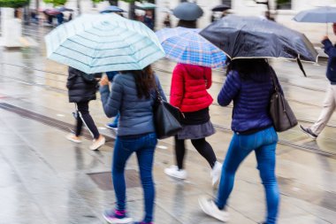 kamera yapılmış hareket bulanıklığı insanların yağmurlu şehirde yürüyüş şemsiyelerle resimle
