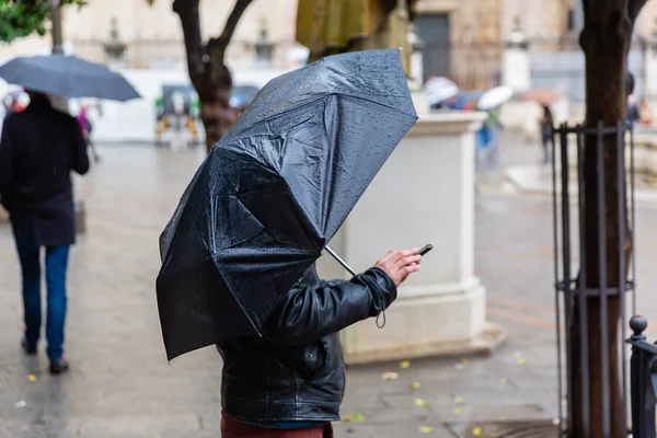 雨の傘を保護しながら携帯電話を扱う人の画像 — ストック写真