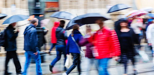 雨の街を歩いて傘を持つ人々 のカメラ作られたモーション ブラー画像 — ストック写真