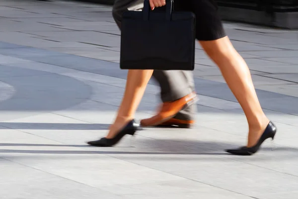 legs of a business woman walking in the city in motion blur