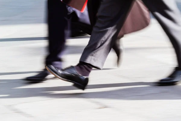 legs of businessmen walking in the city in motion blur