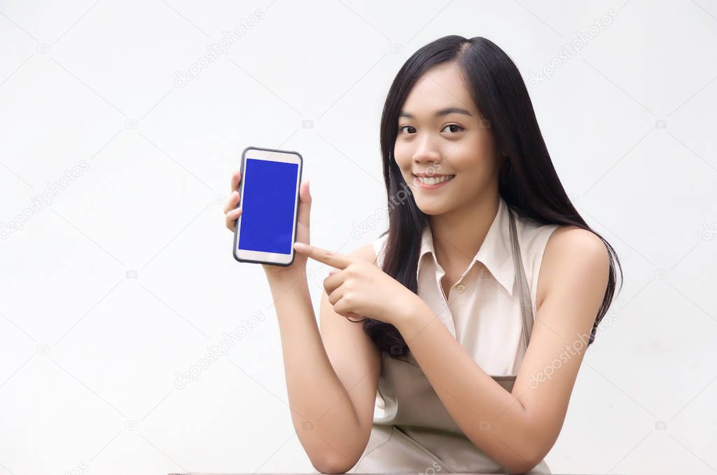 asian lady action to show blank screen on mobile phone as using application. potrait action with wood table and apron suite on white background.