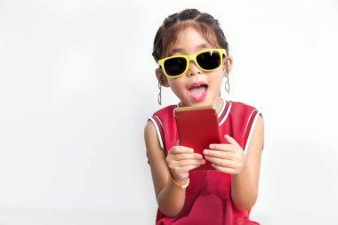 Asyalı çocuk spor gömlek ve güneş gözlüğü moda komik eylem ile cep telefonu beyaz arka planda, dijital nesil kavramı ile