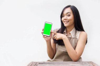 boş ekran cep telefonu uygulamasını kullanarak olarak göstermek için Asya Bayan eylem. Beyaz arka plan üzerinde ahşap masa ve önlük suite ile potrait eylem.