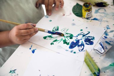 Çocuk el resim bölümü bitki kapatmak ve sulu boya ile kağıt üzerinde sanat yapmak 