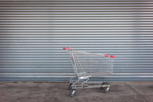 Blank shopping cart on close shop door — Stock Photo, Image