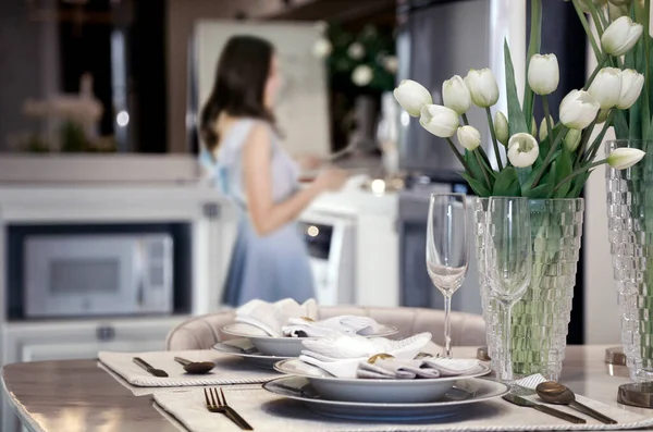 woman wife preparing romantic dinner for aniverary of love on table at home. (focus on flower and kitchenware on dinner table)