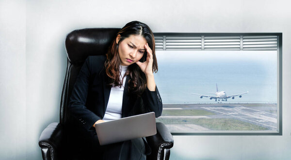 Азиатская деловая женщина беспокоится о работе на ноутбуке в авиационном бизнесе в коронавирусной пандемии, потому что потерял клиента и заблокировать страну и остановить транспорт. 