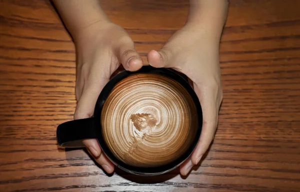 咖啡杯上涂褐色糖浆 手持在木桌上的长颈鹿拿铁艺术 — 图库照片