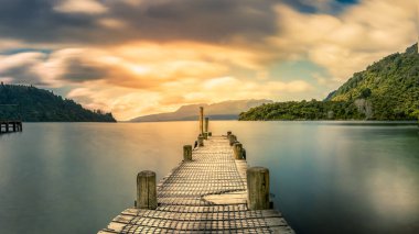 Göl üzerinde turuncu bulutlu gökyüzü ve Tarawera 'da Jetty.