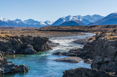 Dağ sıralarıyla çevrili Canterbury NZ 'deki Ahuriri koruma vadisindeki aşırı kurak tarlalar.