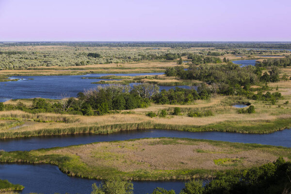 Дельта реки Ворскла в летний день. Природный заповедник Украины. Вид сверху на метеорную равнину в пойме реки. Аэрофотосъемка извилистой реки
