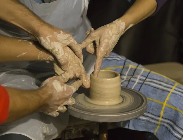 Work with clay. Hands of a potter. Potter teaches people how to make a pot on a potter\'s wheel. Learning pottery