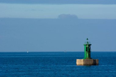 Mavi denizli yeşil deniz feneri, mavi gökyüzü ve soğuk renkler.
