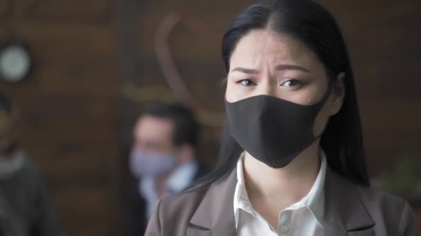 害怕的亚洲女商人戴着保护面具站在同事面前，看着现代办公室里的摄像机。在检疫性验尸官大流行期间做生意.Prores 422 — 图库视频影像