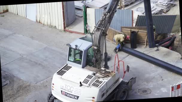 Traktor TEREX přesouvá trubku zavěšenou na kbelíku na staveništi a vytváří tak prostor pro nové stavební materiály. Duben 2020. Kyjev, Ukrajina. Prores 422 — Stock video
