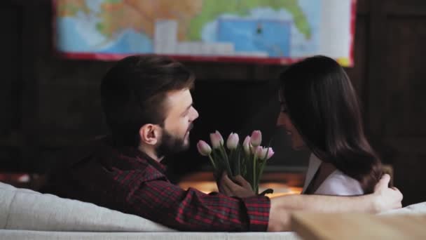 A szerető férj virágot ad a feleségének, aki a nappaliban ül térképpel a falon. Boldog család készül nyaralás választott úti cél. Gyümölcsfélék