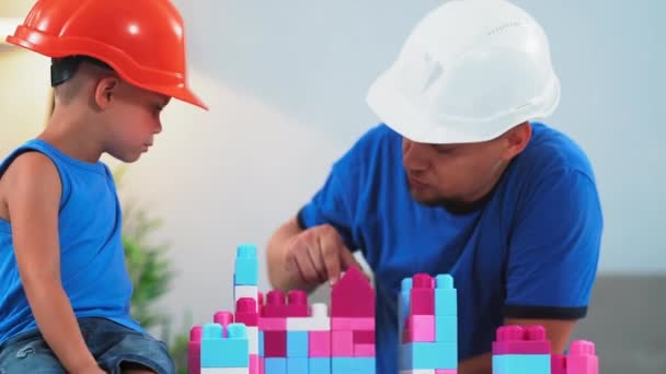 一位父亲和他的儿子一起玩建筑头盔，帮助和指导他如何正确建造城堡。2019.June Kiev, Ukraine.Prores 422 — 图库视频影像