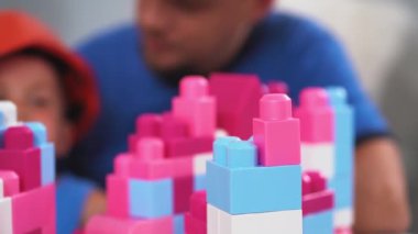 İnşaat işçisi babası ve oğlu inşaat kaskı takıp tuğla inşaatçılığı yapıyorlar. Kale inşa etmede ona yardım ediyorlar. Baba oğul kavramı. Haziran 2019. Kiev, Ukrayna. Prores 422