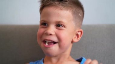 Çocuk yüksek sesle kahkaha atar, ağzı şekerle doludur. Anne eli saçlarını düzeltirken çocuk kusar. Ebeveynler ve çocuklar konsepti. Haziran 2019. Kiev, Ukrayna. Prores 422