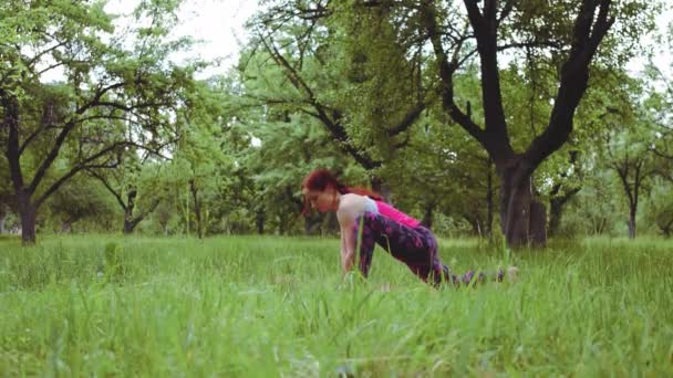 Девушка инструктор йоги протягивая вне дома с позой бокового угла вращения, вариация Utthita Parsvakonasana требует много гибкости, чтобы повернуть так глубоко и заземлить задний каблук. Прорес 422 — стоковое видео