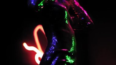 Yarı aydınlık stüdyoda dans eden seksi sarışın kız. Afro-Amerikalı kız, parlak bir elbiseyle neon soyut ışıklı fotoğraf stüdyosunda dans ediyor. Neon konsepti. Prores 422