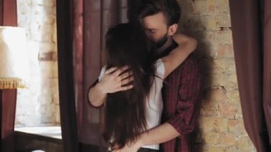 Genç çift oturma odasında öpüşüp kucaklaşıyorlar. Beyaz tişörtlü kadın kocasına deli gibi aşık. Adam kadını nazikçe okşar. Dikiz aynası. Aile kavramı. Prores 422