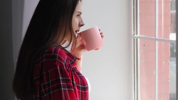 Estudiante con taza de café o té mirando a la ventana. Autoaislamiento durante el período de cuarentena. Concepto educativo. Enfoque selectivo en el libro. Prores 422 — Vídeos de Stock