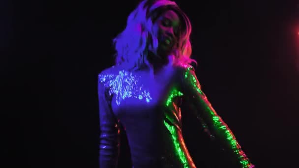 Ragazza afroamericana che balla felice davanti a un muro di luci al neon. Ragazza con un vestito di paillettes d'argento nel night club. Concetto al neon. Prore 422 — Video Stock