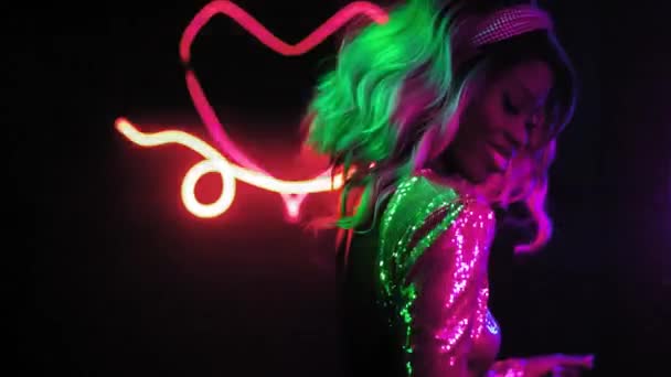 Sexy afroamerikanische Blondine tanzt im Disco-Shutter-Licht selbst in Neon-Figuren und in einem silbernen Paillettenkleid vor schwarzem Hintergrund. Neon Konzept. Prores 422 — Stockvideo