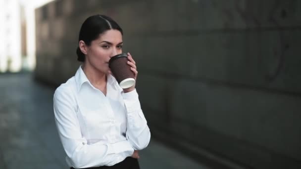 Ділова жінка п'є каву в діловому одязі, що стоїть на відкритому повітрі біля офісної будівлі. Кавова перерва для ділових людей. Бізнес-концепція. Пропозиції 422 — стокове відео