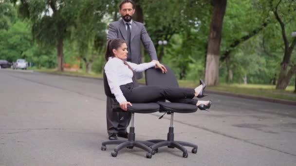 En man knuffar en stol med en tjejchef på gatan där han hånar anställda. Flickan får anställda att underhålla henne. Trakasserier på jobbet. Prores 422 — Stockvideo