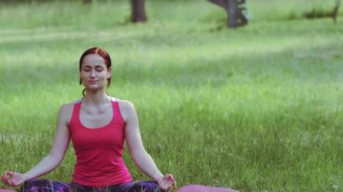 Kamera kaydırma Yoga eğitmeni kız meditasyon yaparken nefes alma tekniği uyguluyor parkta ya da bahçede egzersiz yapıyor. Prores 422