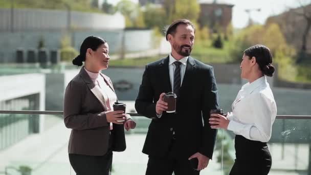 Geschäftsleute und Frauen, die draußen in Businesskleidung Kaffee trinken, stehen in der Nähe von Bürogebäuden. Geschäftsleute bei einer Kaffeepause. Geschäftskonzept. Prores 422 — Stockvideo