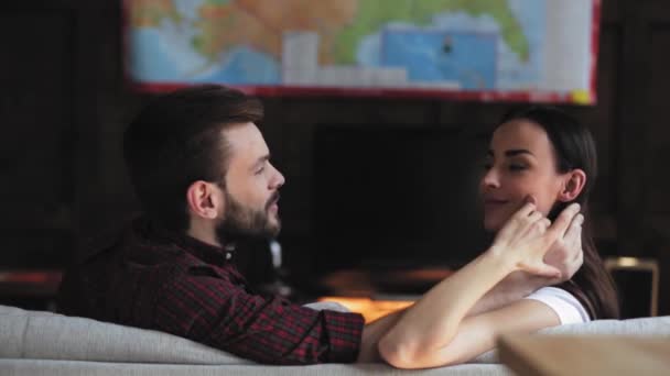 Les jeunes communiquent en discutant des décisions importantes à l'intérieur de la maison tout en étant assis sur le canapé dans le salon. Charmant jeune couple aimant embrassant d'accord. Prores 422 — Video