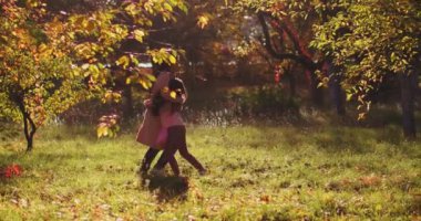 Kızı olan sevgili anne, Golden Autumn Parkı 'nda peri masalı renginde ağaçların arasında el ele tutuşarak eğleniyor. Renkli görüntüler. Uzayı kopyala Aile kavramı. Prores 422