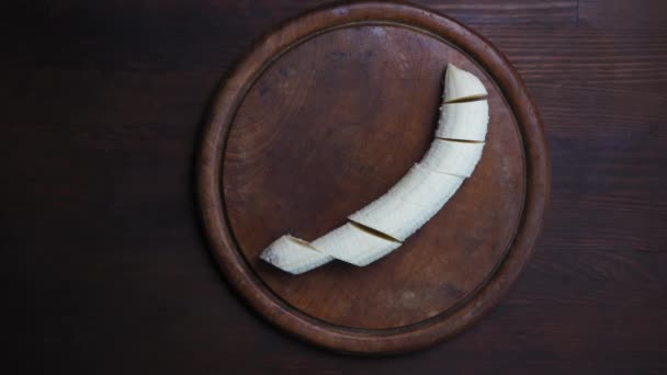 まな板に刻んだ皮をむいたバナナの動きの映像はありません。濃い木製のテーブルの上に大きな平和バナナスライス。第四百二十二条 — ストック動画